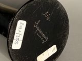 a black vase with a label on it sitting on a table