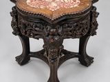 une table richement sculptée, avec un plateau en marbre et des pieds en bois