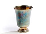 a small silver cup sitting on a white surface