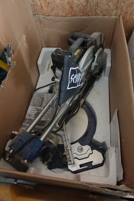 une boîte en carton posée par terre, contenant des outils