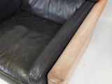 a black leather couch with a tan leather arm