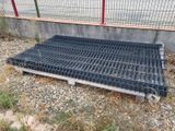 a metal grate laying on the ground next to a fence