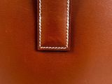 a close up of a brown leather purse with white stitching