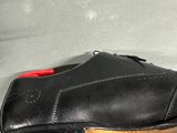 a black shoe with a red button on it