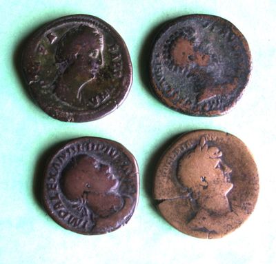 three old roman coins sitting on top of a green surface