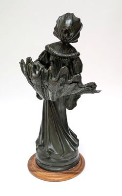 bronze statue of a woman holding a bird on a wooden base