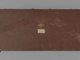 an old suitcase sitting on top of a table with a tag on it