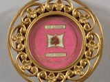 une image représentant une broche rose et dorée ornée d'une rose au centre