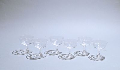 six wine glasses are lined up on a white surface