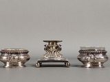 trois vases en argent posés les uns à côté des autres sur une table