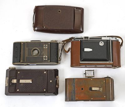 plusieurs vieux appareils photo sont alignés sur une surface blanche