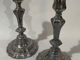 two silver candlesticks sitting on a white surface