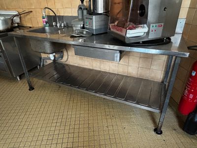 une cuisine avec une table en inox et un extincteur rouge à côté
