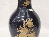 a black vase with gold flowers on it on a white background