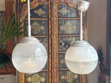 two lamps that are hanging from the ceiling above a cabinet