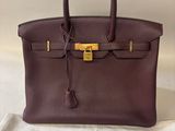 a brown leather bag sitting on top of a white cloth