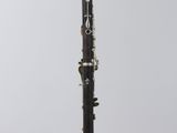 a black and silver clarinet sitting on top of a white pedestal