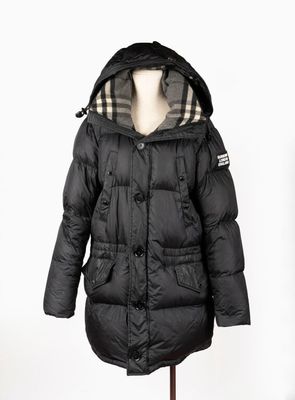 La veste est noire et est dotée d'une capuche.