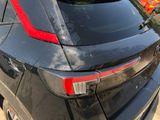 the rear end of a black car with a red stripe on it