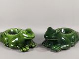 deux grenouilles en céramique verte assises l'une à côté de l'autre sur une surface blanche