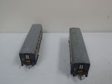 two toy trains sitting side by side on a white surface