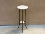 une petite table blanche avec un piètement doré, posée à même le sol