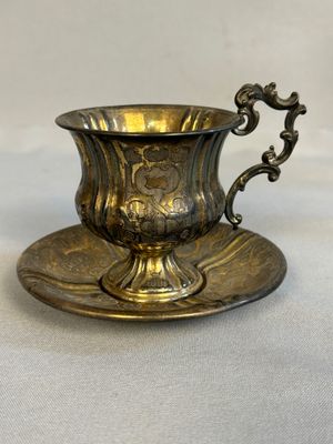 an antique silver cup and saucer on a saucer on a table