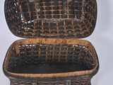 a small wicker box with a handle on a white surface