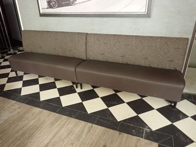 une photo d'un banc dans un restaurant, avec une voiture en arrière-plan