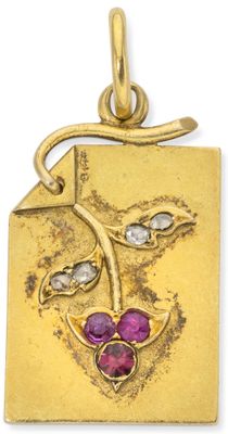 a close up of a gold pendant with a purple flower on it