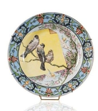 une assiette décorée d'oiseaux, posée sur un socle