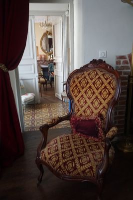 une chaise rouge et dorée dans une pièce avec une cheminée