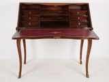 an antique writing desk with a red leather top and brass hardware