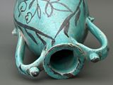a blue vase with a handle on it on a table