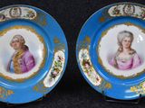 une paire d'assiettes bleues et dorées représentant le portrait d'une femme et d'un homme