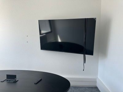 une table noire sur laquelle est posé un téléphone portable, devant un téléviseur à écran plat