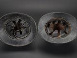 pair of old metal plates with holes in them sitting on a table