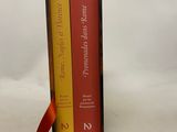 two books in a box with a red ribbon on a white background