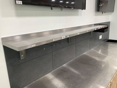 stainless steel counter top in a commercial kitchen with a flat screen tv on the wall