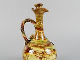a brown and yellow vase with a handle on a table