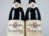 two bottles of red wine sitting next to each other on a table