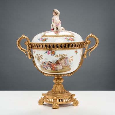 un bol blanc et doré surmonté d'une figurine