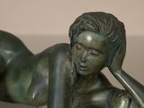 a bronze statue of a woman laying on her stomach