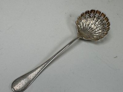 a silver spoon with a shell shaped handle on a table