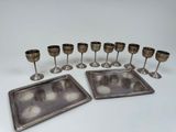 several silver plated wine glasses and trays on a white surface