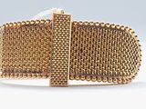 gros plan d'un bracelet en or sur une surface blanche