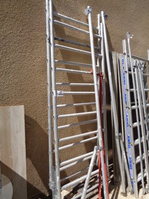 Plusieurs échelles sont alignées contre un mur près des toilettes.