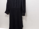 the black jumpsuit is hanging on a hanger on the wall