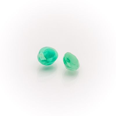 a pair of green glass beads on a white surface