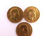 three gold coins sitting on top of each other on a white surface